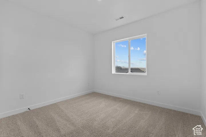 Neutral-toned carpeted flooring with a white trim, large window with white framing, and white painted walls