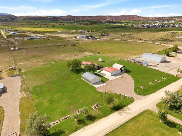 Expansive property featuring multiple outbuildings, mature trees, and a gravel driveway