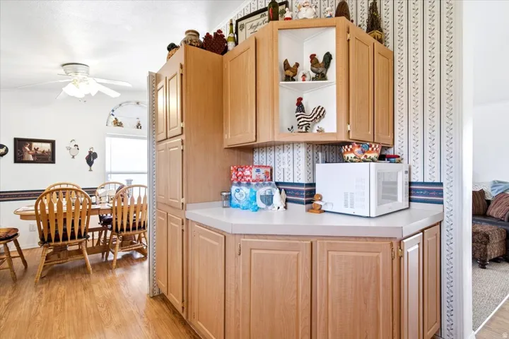 Wood-finish flooring, light-toned cabinetry, built-in pantry, and a ceiling fan