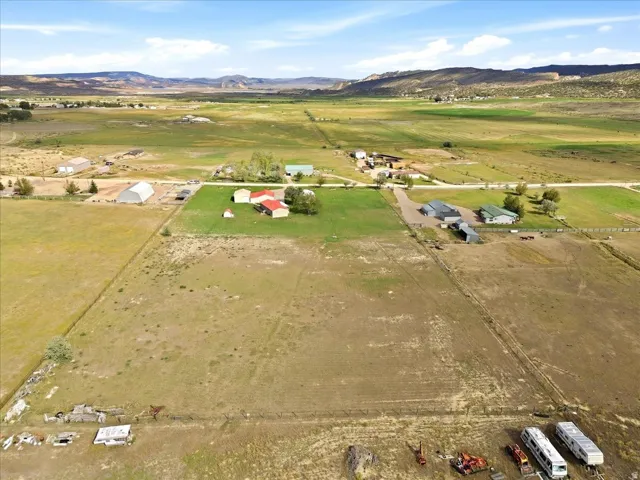 Expansive rural property featuring multiple structures, open fields, and distant mountain backdrops