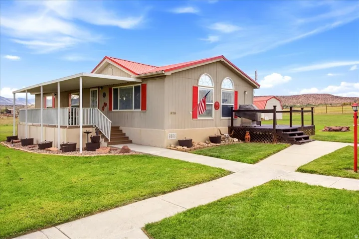 Pitched red roof, covered front porch, elevated wood deck, arched windows, and concrete pathways