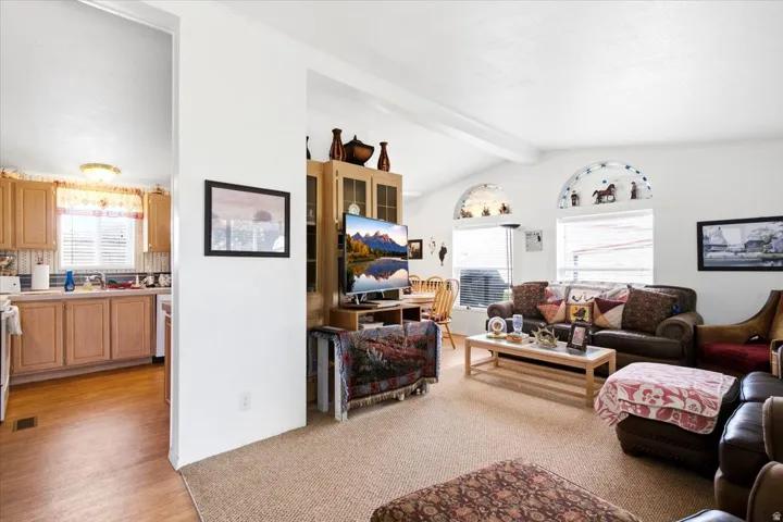 Vaulted ceiling with exposed beams, arched accent windows, wood-finish flooring, and built-in cabinetry
