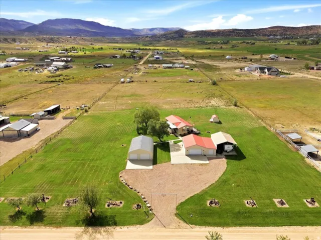 Expansive property featuring a residence with a red roof, multiple outbuildings, and a large gravel driveway