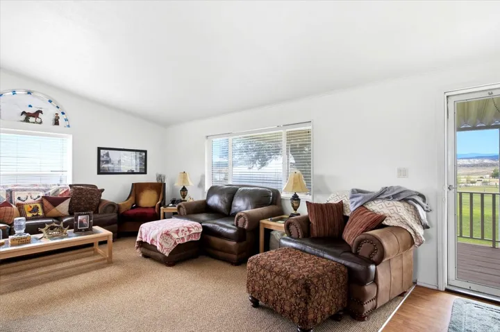 Vaulted ceiling, arched window, multiple large windows, exterior door with glass panel, and wood-finish flooring