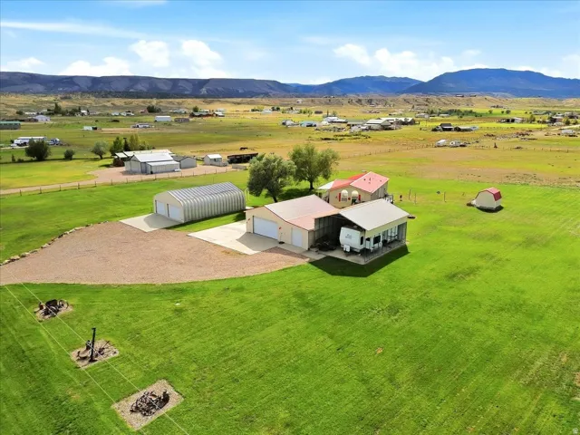 Expansive green landscape with a residence, detached garage, and an additional metal outbuilding