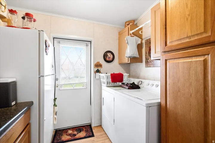 Laundry area featuring wood-finish flooring, wood cabinetry, and a white exterior door with integrated blinds