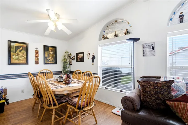 Vaulted ceiling with a ceiling fan, arched wall cutouts, wood-finish flooring, and large windows with blinds