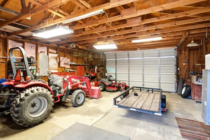 Expansive garage space featuring exposed wood beam ceiling, concrete flooring, and a large roll-up garage door