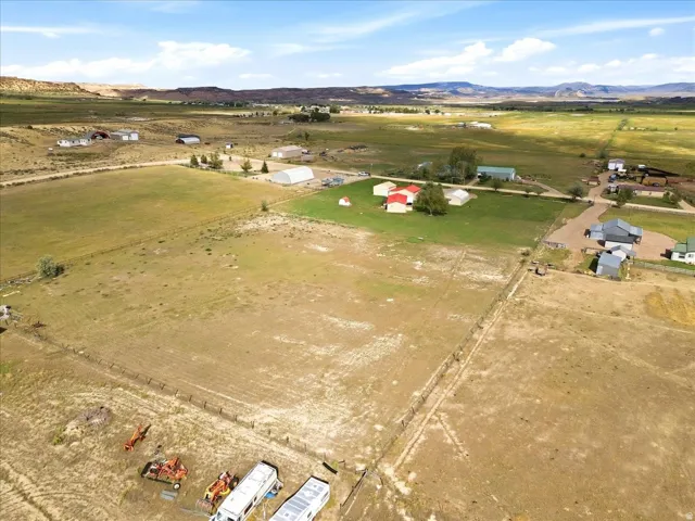 Expansive rural property featuring multiple structures, open fields, and distant mountain ranges