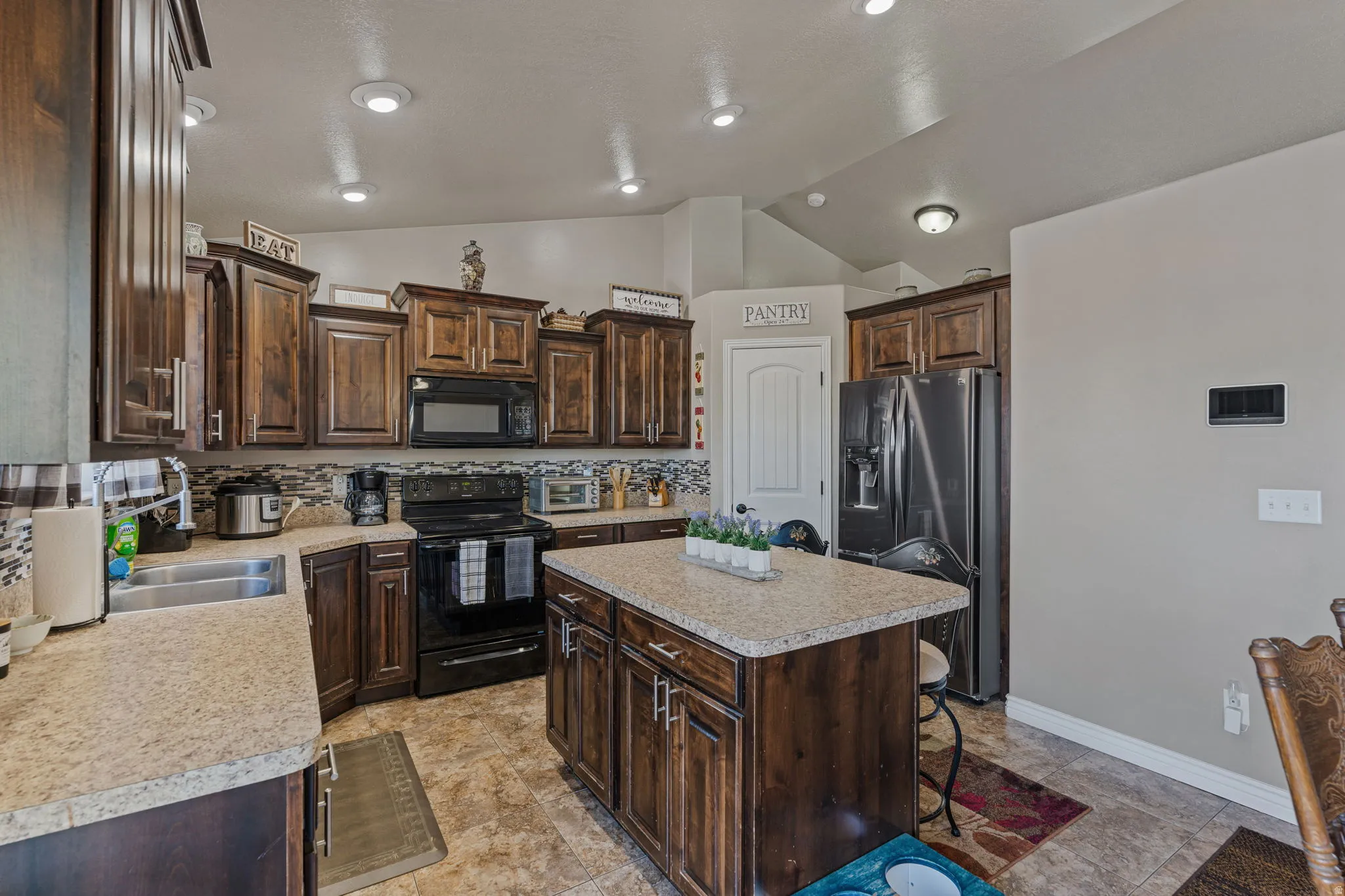 Kitchen featuring wood cabinetry, light-toned countertops, a center island with storage, tile flooring, and recessed lighting