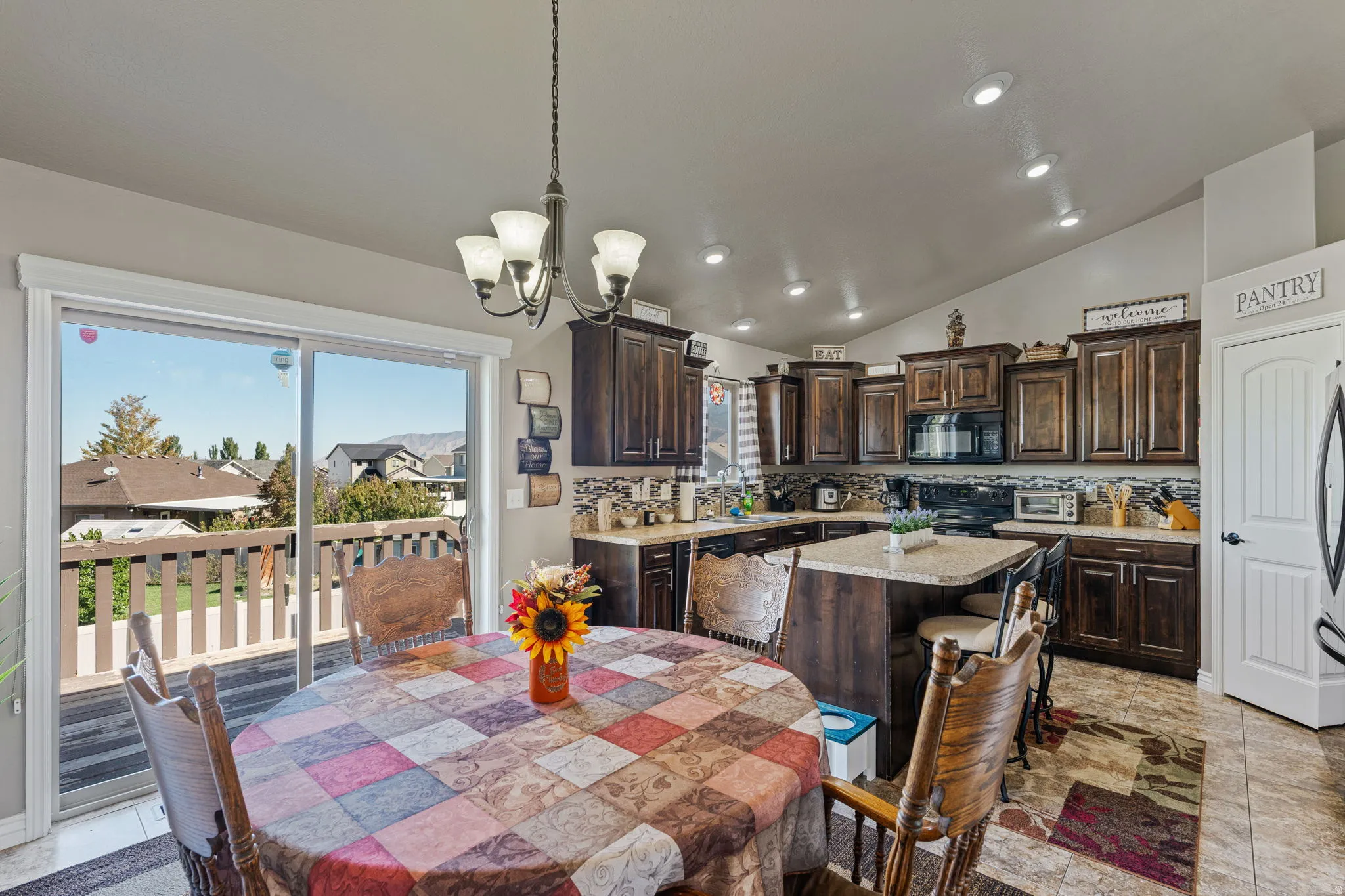 Kitchen featuring dark wood-finish cabinetry, granite-style countertops, mosaic tile backsplash, and a central island with seating