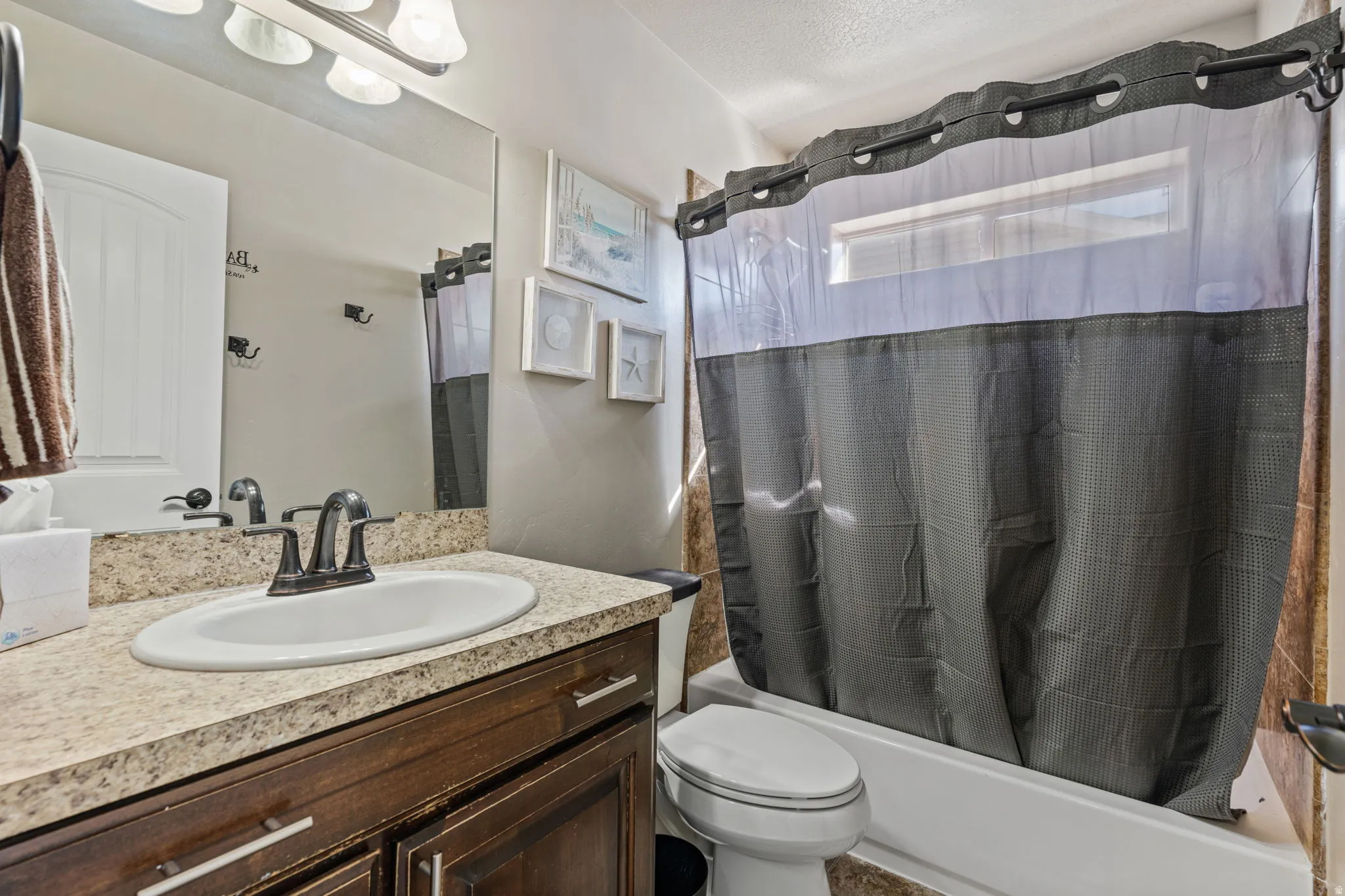 Vanity with a laminate countertop, undermount sink, dark wood-finish cabinetry, and a bronze-finish faucet