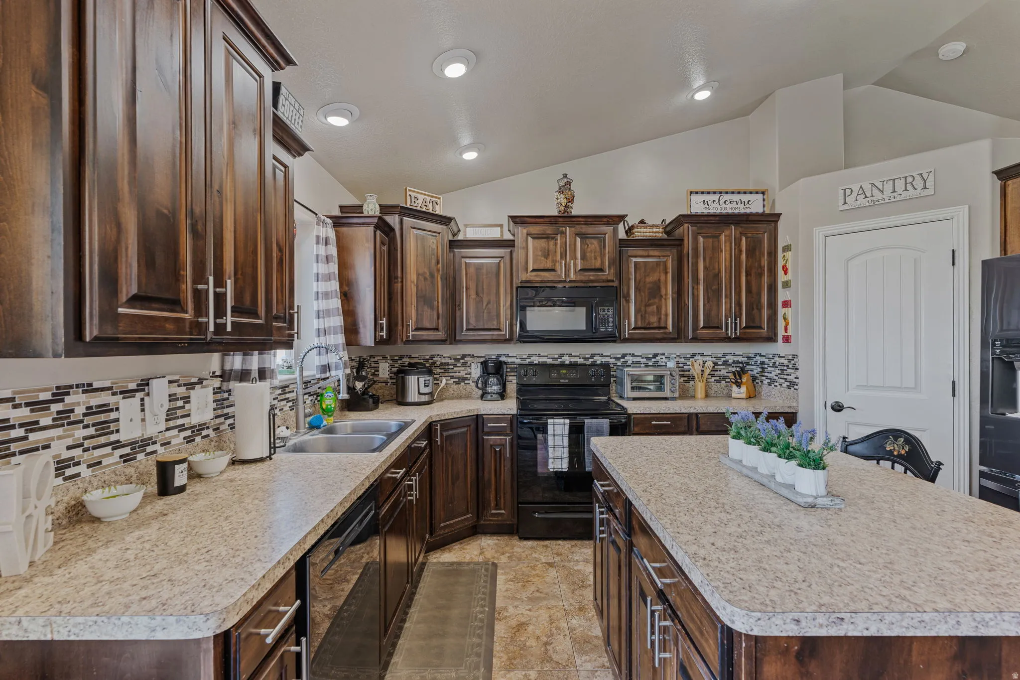 Extensive dark wood-finish cabinetry, light-toned countertops, and a full tile backsplash