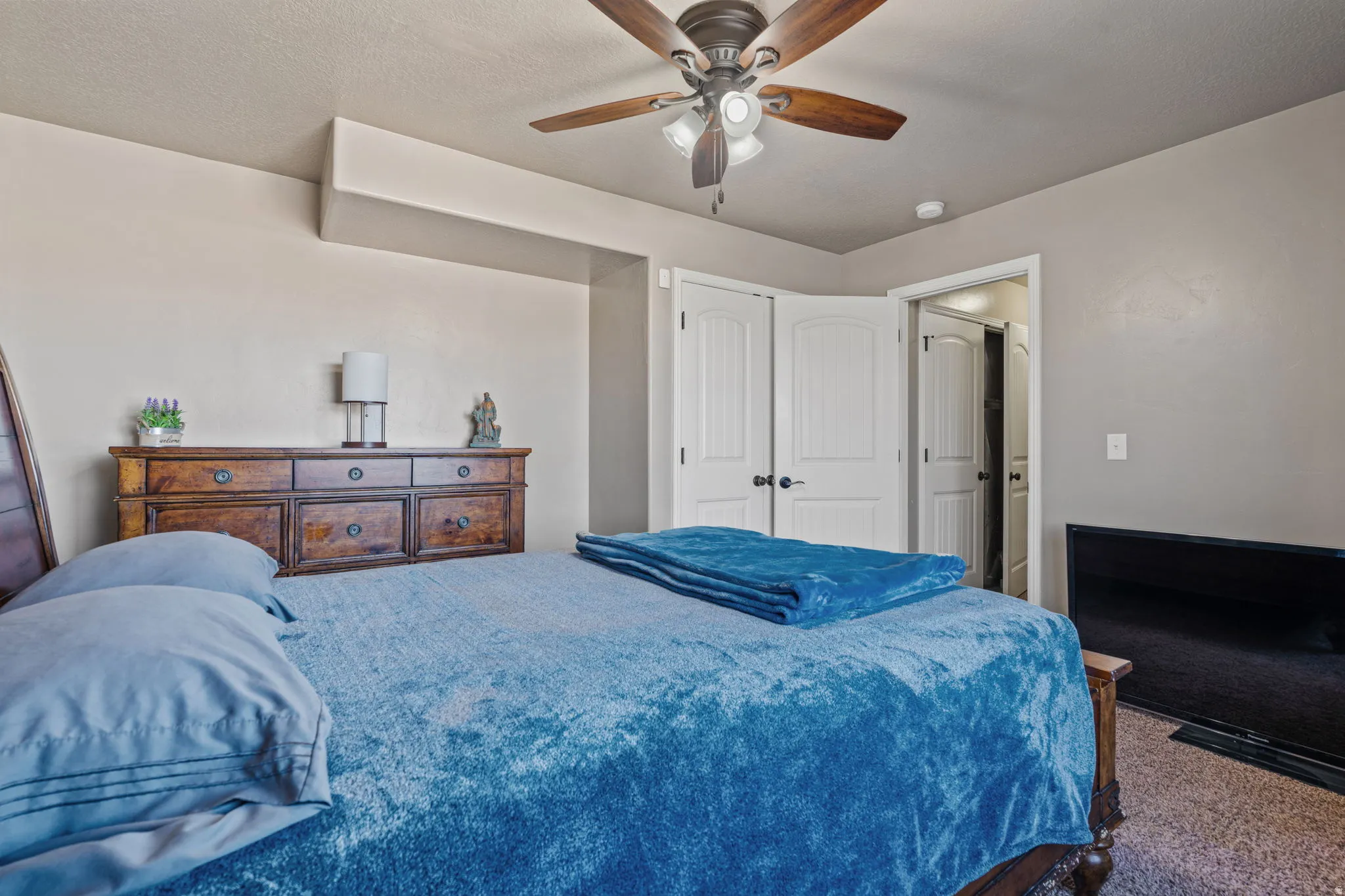 Ceiling fan with light fixture, double closet doors, and wood-finish flooring
