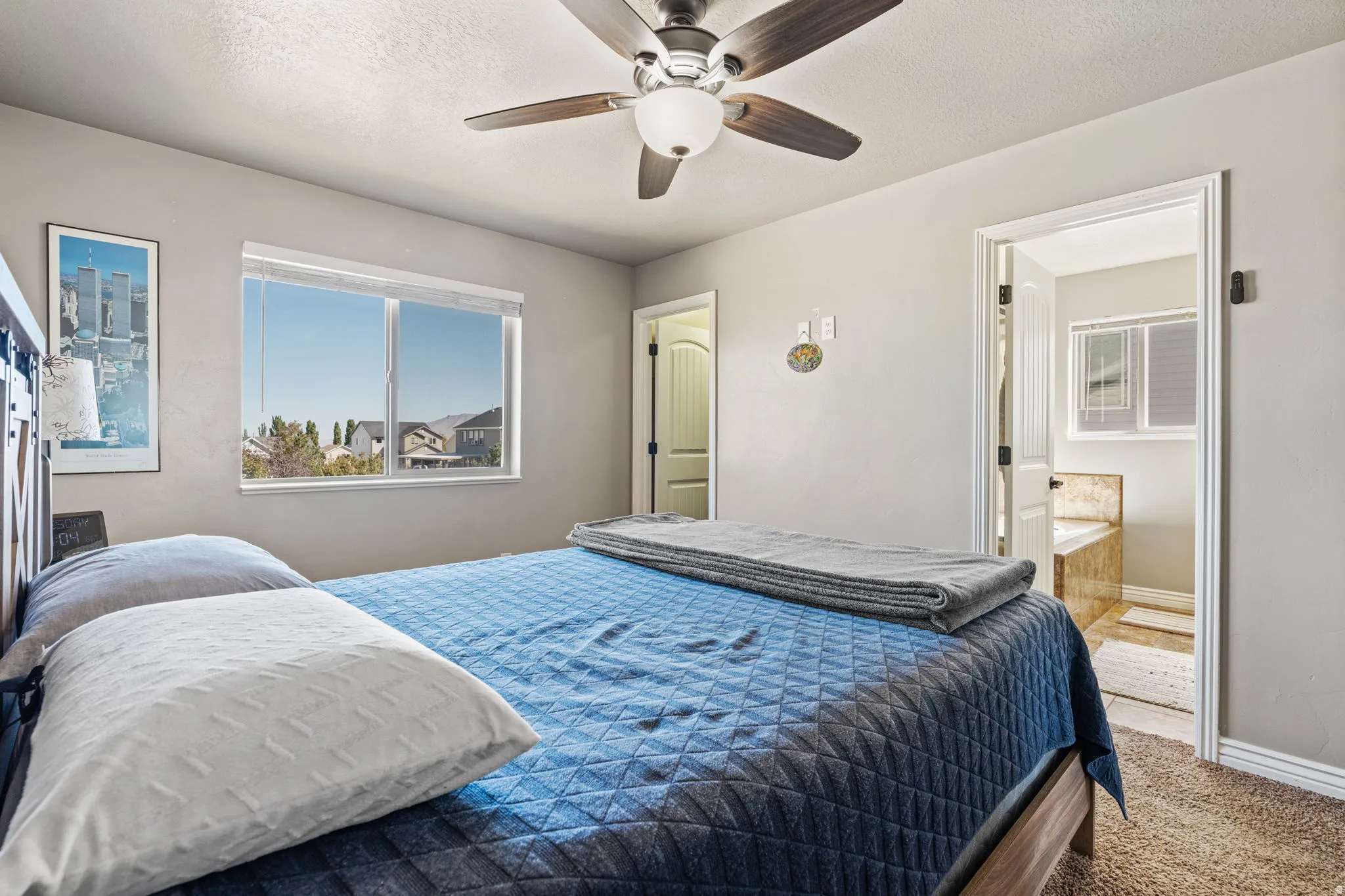 Bedroom with wood-finish ceiling fan, neutral wall paint, and carpet flooring