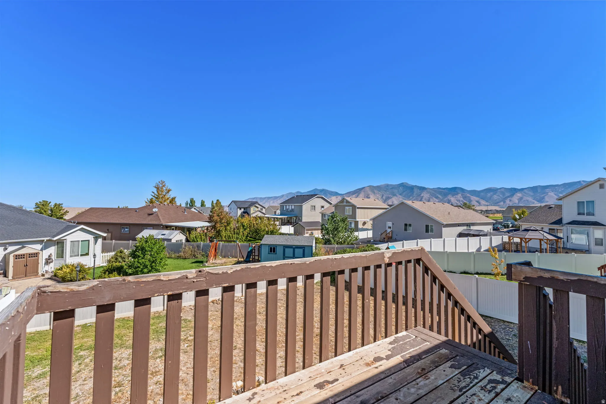 Expansive backyard featuring a partial privacy fence, a storage shed, and distant mountain scenery
