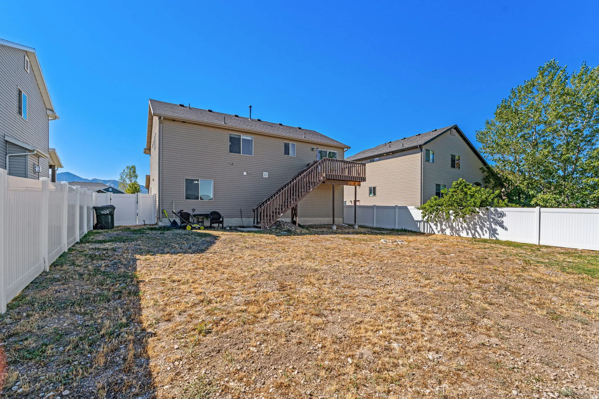 Expansive backyard with a full-height privacy fence and a second-story wooden deck with stairs