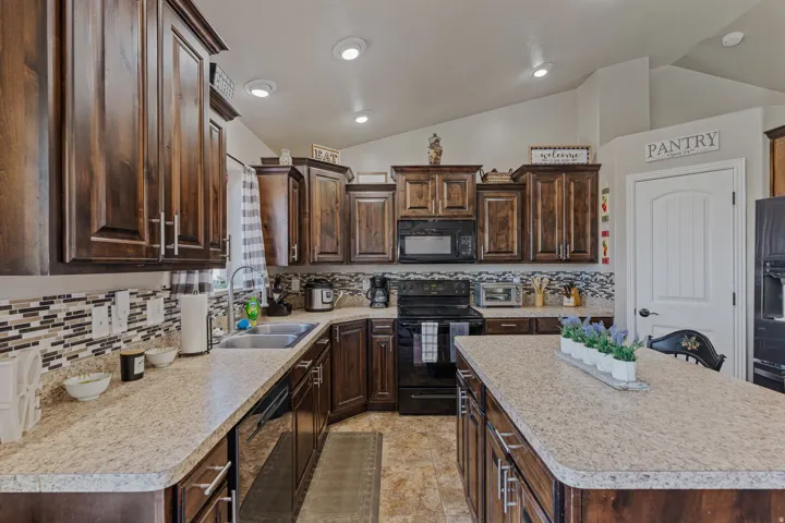 Extensive dark wood-finish cabinetry, light-toned countertops, and a full tile backsplash
