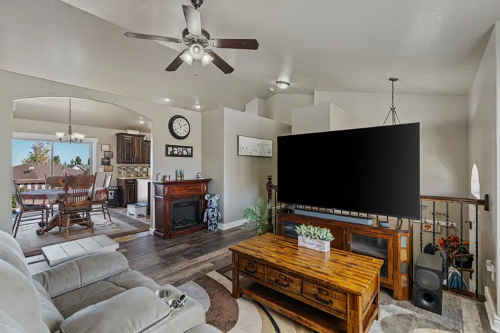 Arched entryway to the dining area, wood-finish flooring, ceiling fan, decorative fireplace, and wrought iron railing
