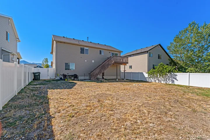 Expansive backyard with a full-height privacy fence and a second-story wooden deck with stairs