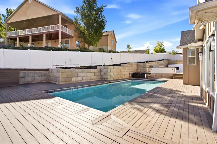In-ground swimming pool with integrated spa and composite decking