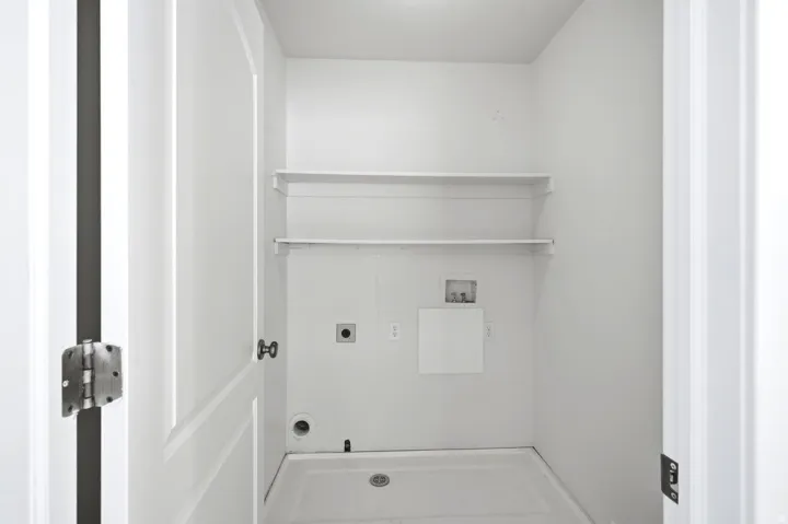 Laundry area featuring a utility sink, two wall-mounted shelves, and appliance hookups