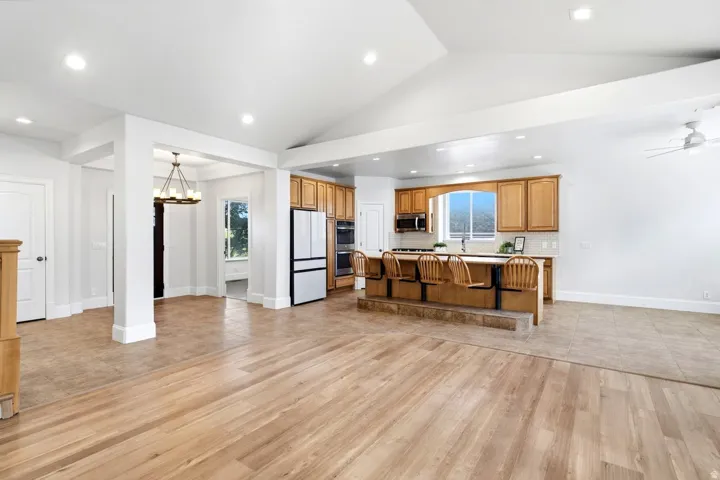 Vaulted ceiling with recessed lighting, wood-finish flooring, kitchen island with integrated seating, oak cabinetry, and stainless steel appliances