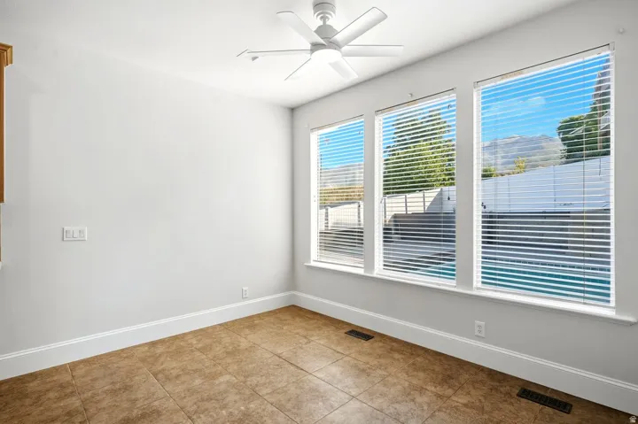 Ceramic tile flooring, white walls, triple window configuration, white window blinds, and a ceiling fan