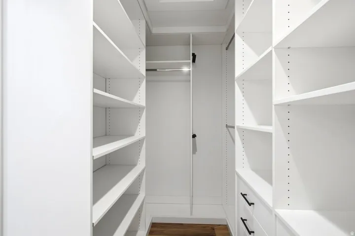 Built-in closet system featuring multiple adjustable shelves, hanging rods, and integrated drawers with matte black hardware