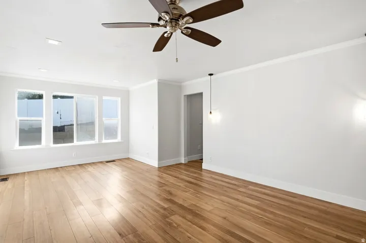 Wood-finish flooring, white walls, multiple windows, ceiling fan, and recessed lighting