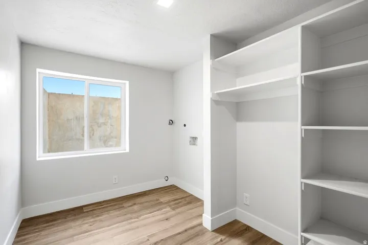 Built-in shelving and hanging rod with wood-finish flooring, recessed lighting, and a window