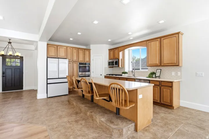 Kitchen featuring wood cabinetry, stainless steel appliances, a center island with seating, and tile flooring
