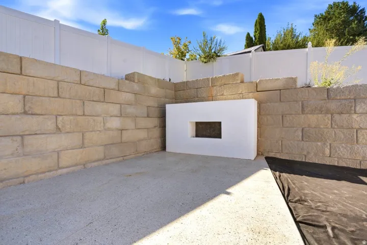Retaining wall construction with integrated stucco feature, concrete patio, and privacy fencing
