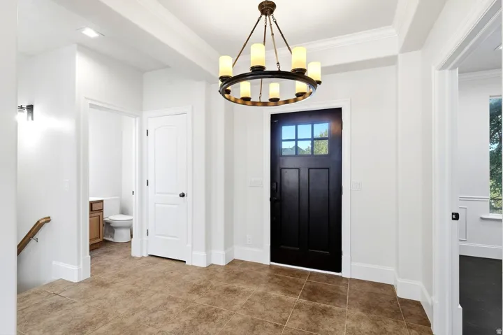 Entryway featuring a dark wood paneled door with glass inserts, recessed lighting, crown molding, and tiled flooring