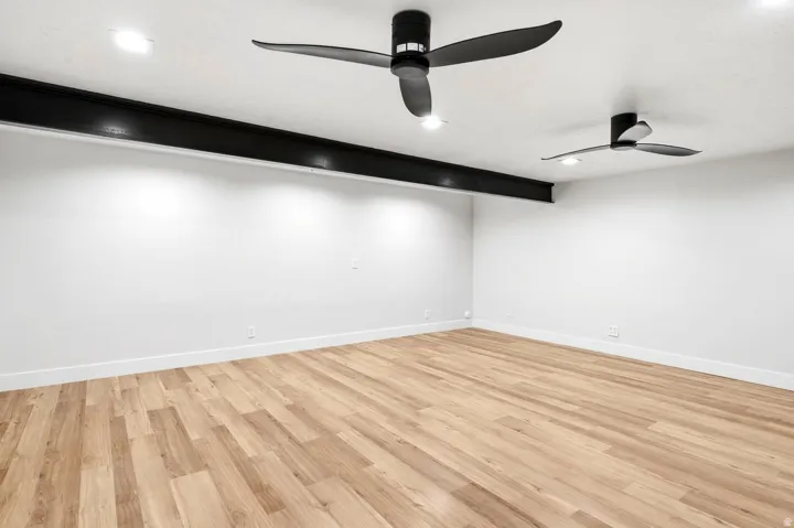 Hardwood-style flooring, white walls, and a recessed lighting system