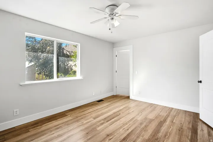 Wood-finish flooring, white walls, and a ceiling fan with light fixture