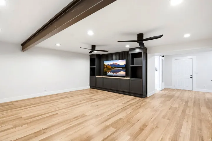 Expansive room with wood-finish flooring, recessed lighting, and a built-in media center