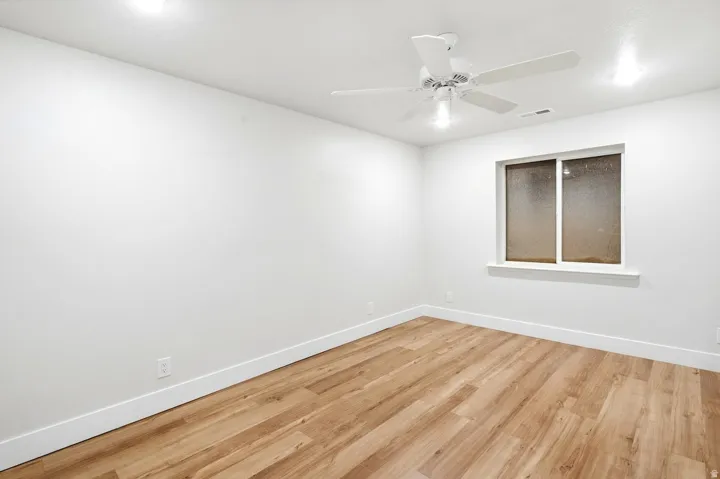 Wood-finish flooring, white walls, recessed lighting, ceiling fan, and a window with white trim
