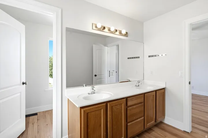 Double vanity with wood-finish cabinetry, integrated sinks, and polished chrome fixtures