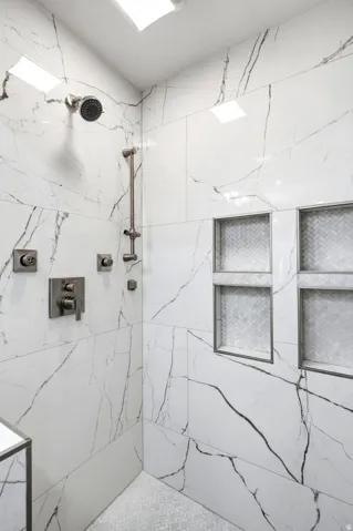 Shower enclosure with large format tile walls and two recessed niches
