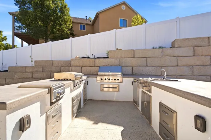 Outdoor kitchen with built-in stainless steel grill, integrated cooktop, and sink