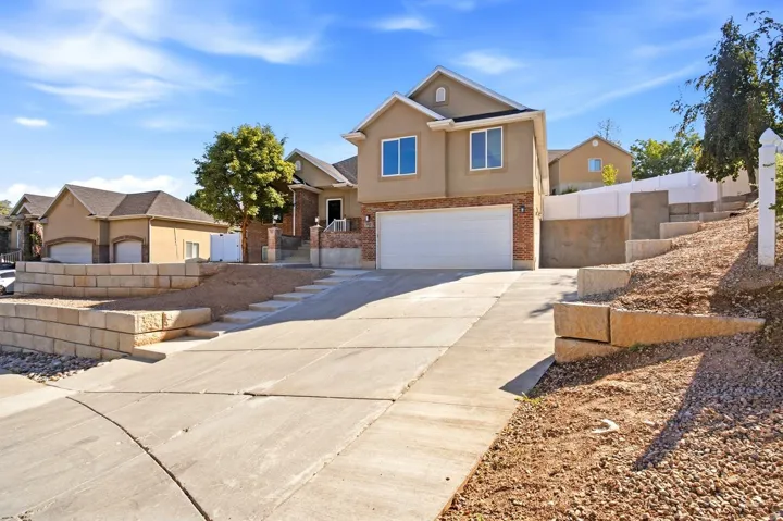 Multi-level exterior with stucco and brick accents, an attached two-car garage, and a concrete driveway
