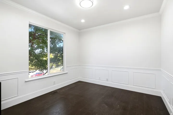 Dark wood-finish flooring with white wainscoting and crown molding