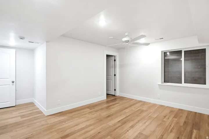 Recessed lighting, wood-finish flooring, ceiling fan, white trim, and a white window frame