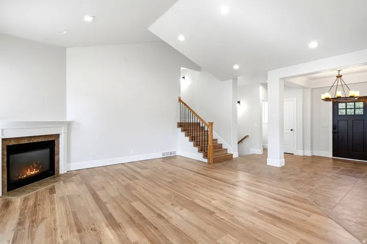 Spacious interior featuring a corner fireplace with a white mantel, wood-finish flooring, and recessed lighting