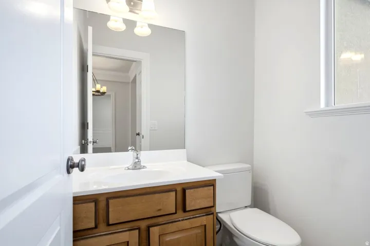 Bathroom with a wood-finish vanity, integrated sink, wall-mounted mirror, and a window with frosted glass