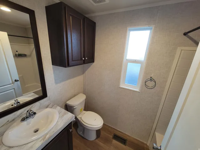 Bathroom featuring a vanity with an integrated sink, dark wood-finish cabinetry, a window, and wood-finish flooring