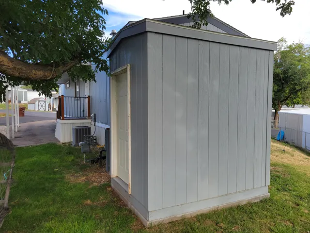 Exterior storage shed with vertical siding, a solid entry door, and a finished roofline