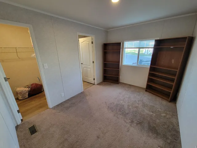 Carpeted room with a window, recessed ceiling lighting, and two interior doorways