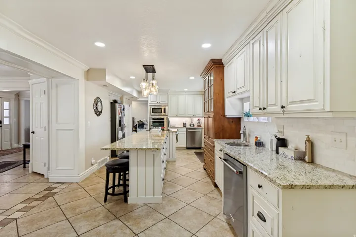 Kitchen featuring white cabinetry, light-colored countertops, stainless steel appliances, a center island with seating, and tile flooring